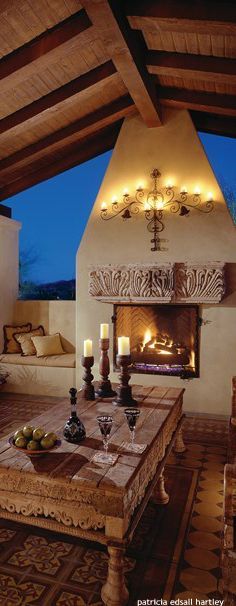 an outdoor living room with fireplace and couches in it at night, lit by candles