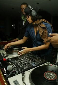 two people are djing in front of a turntable with headphones on their ears