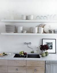 the kitchen is clean and ready to be used for dinner or lunchtime, with dishes stacked on shelves above the sink