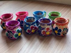 there are many colorful vases sitting on the table with different colors and designs painted on them