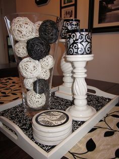 a white candle holder sitting on top of a table next to a vase filled with black and white balls