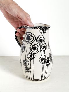 a hand is holding a black and white vase