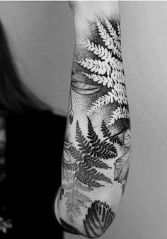 a woman's arm with a fern tattoo on it