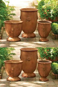 four large planters sitting in the middle of a walkway surrounded by potted plants