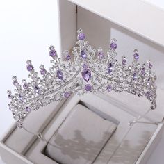 a tiara in a white box with purple and clear stones on the side,