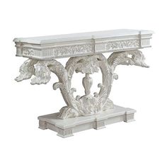 an ornate white console table with marble top and carved details on the base, against a white background