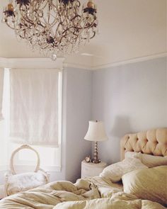 a chandelier hanging from the ceiling above a bed in a room with blue walls