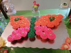 there is a cake shaped like a butterfly on top of a table with cupcakes in the shape of flowers