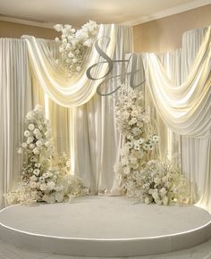 a wedding stage with white flowers and drapes