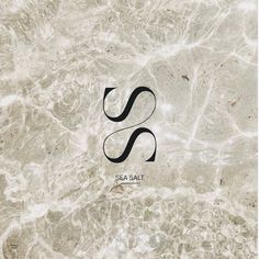 the sea salt logo is shown in black on a white marble surface with water swirling around it