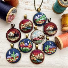 six embroidered pendants with spools of thread next to them