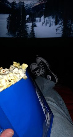 a person holding a blue bag full of popcorn in front of a mountain view at night