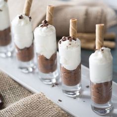 small desserts are lined up on a tray with marshmallows and chocolate