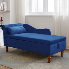 a blue chaise lounger sitting on top of a rug in front of a window