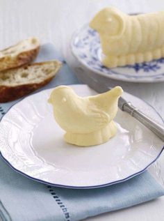 two plates with slices of bread on them and a piece of butter in the shape of a bird