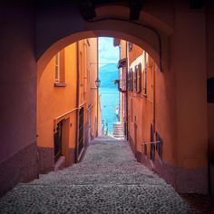 an alley way with orange buildings and water in the background