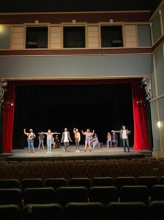 a group of people standing on top of a stage in front of red curtained walls