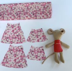 a stuffed animal next to sewing supplies on a white surface with pink and purple flowers