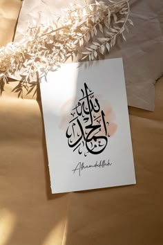 a piece of paper with an arabic calligraphy written on it next to some leaves