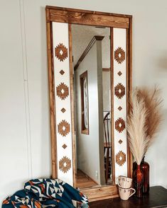 a mirror sitting on top of a table next to a vase