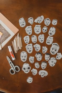 a wooden table topped with cut out pictures of babies'faces next to scissors and glue