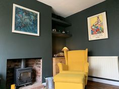 a yellow chair sitting in front of a fireplace next to a painting on the wall