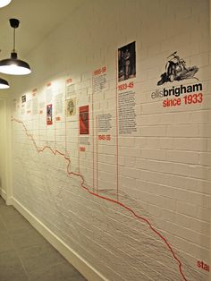 a white brick wall with posters on it and lights hanging from the ceiling in an office building