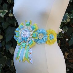 a pregnant woman wearing a blue and yellow sash with flowers on it's belt