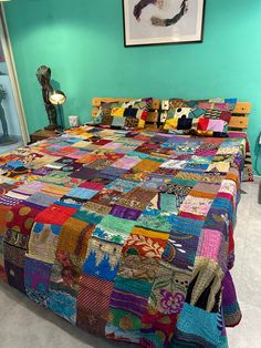 a bed with a colorful quilt on top of it in a room next to a painting