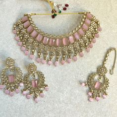 Stylish antique gold choker set with matching earrings and tikka. A light weight antique gold choker adorned with champagne zircon crystal and pink beadwork. Measurements (Approxiamtely) Choker 2.75 (Adjustable with string  Tikka  2.5 inch pendant x 1 inch x 2 inch pearl chain Earrings 2.5 inch x 1 inch  Ready to ship! Pink Round Jewelry Sets For Diwali, Bollywood Style Pink Jewelry Sets For Festivals, Pink Desi Jewelry, Pink Bollywood Jewelry Sets For Gifts, Heavy Pink Bollywood Jewelry Sets, Antique Gold Choker Set, Gold Choker Set, Pink Choker, Choker Set