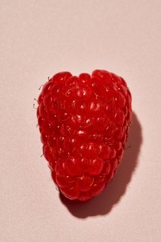 a heart shaped raspberry sitting on top of a pink surface