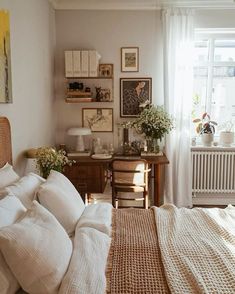 a bed sitting in a bedroom next to a window with lots of pillows on top of it