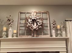 an old window frame is decorated with flowers and candles on top of a mantel