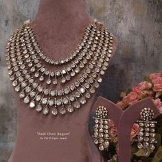 the necklace and earrings are on display in front of a pink dress with floral bouquets