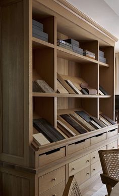 a wooden bookcase with many books on it in a living room next to a window