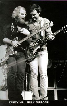 two men standing next to each other with guitars