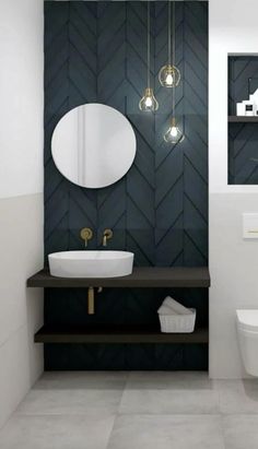 a white toilet sitting next to a bathroom sink under a round mirror on a wall