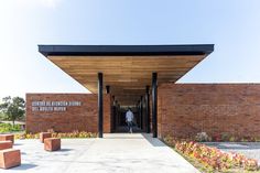 a brick building with benches in front of it and a man walking into the entrance