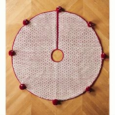 a red and white round rug with pom - poms on the bottom is sitting on a wooden floor