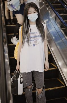 a woman wearing a face mask standing on an escalator