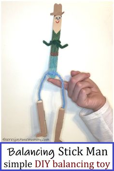 a hand holding a stick man made out of paper and rope with the words balancing stick man simple diy balancing toy