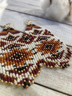 a pair of beaded earrings sitting on top of a wooden table