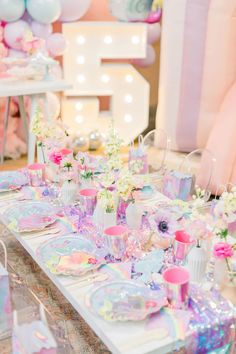 a table set up for a birthday party with pink and blue decorations, balloons and flowers