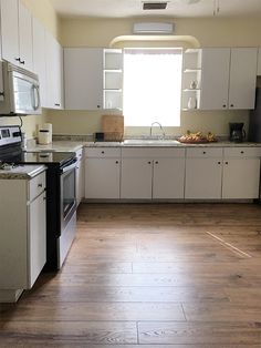 an empty kitchen with white cabinets and wood flooring is seen in this image from the doorway