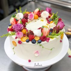 a white cake topped with fresh fruit and flowers