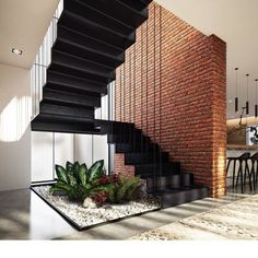 an indoor stair case with plants and rocks on the ground next to it, in front of a brick wall