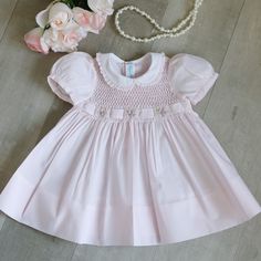 This Sweet Little Smocked Dress Is Precious! So Many Details!!! The Dress Is Done In A Cotton Blend In A Pale Pink Hue. The Bodice Is Fully Smocked In A Honeycomb Design. The Smocking Is Bordered By More Smocking That Is Done In An Accordion Style. A Matching Pink Belt Weaves Through The Smocking. In Between The Woven Belt Are Hand Embroidered Floral Bouquets Done In Pink, Lavender And Dusty Rose. Yellow And White Bullion Rosebuds Surround The Embroidered Roses. The Short Puff Sleeves Have A Mat Heirloom Embroidery, Smocking Tutorial, Hand Smocked Dress, Smocked Baby Dresses, Toddler Dresses, Pink Belt, Embroidered Roses, Vintage Baby Clothes, Pinterest Ideas