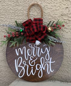 a wooden sign that says merry and bright hanging from the side of a building with a bow on it