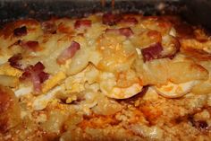 a close up of food in a pan on a stove top with meat and cheese