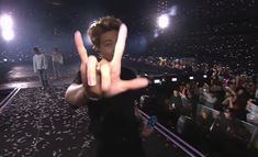 a man making the v sign with his hand at a music concert in front of an audience